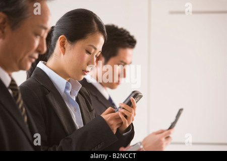 Three business executives using their mobile phones Stock Photo