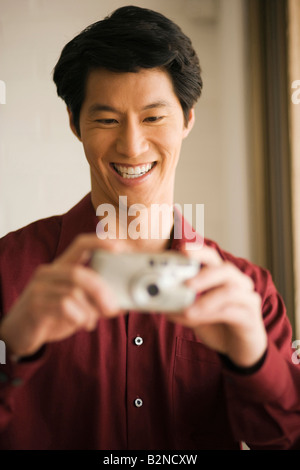 Young man holding a digital camera and smiling Stock Photo