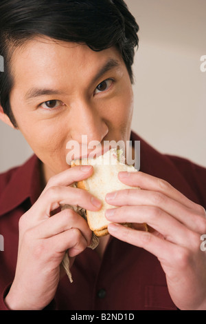 Portrait of a young man eating a sandwich Stock Photo
