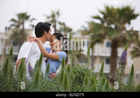 Young man kissing at forehead of a young woman, Huntington Beach, California, USA Stock Photo
