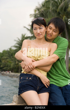 Mid adult man embracing a mid adult woman on the beach and smiling Stock Photo