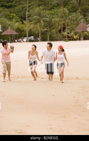 Two couples walking on the beach Stock Photo