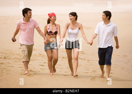 Two couples walking on the beach Stock Photo