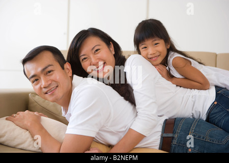 Portrait of a mid adult woman with her daughter lying on a mid adult man, Singapore Stock Photo