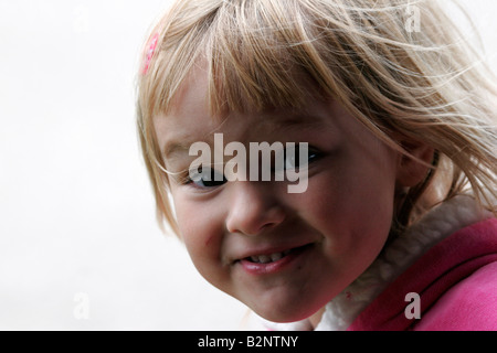 A young girl smiling with a quirky smile who looks like she is up to mischief Stock Photo