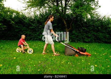 Son with father while mowing the lawn green grass garden Stock Photo