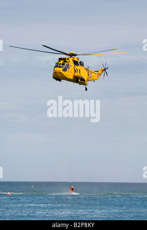 The RAF Sea King rescue helicopter with winchman deployed recovering the survivor from the sea Stock Photo