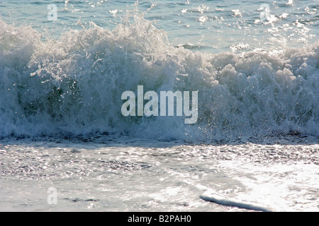 A backlit wave breaking on the shore Stock Photo