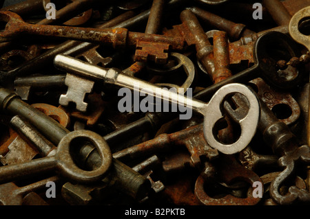 A shiny skeleton key among a pile of old rusted antique keys Stock Photo