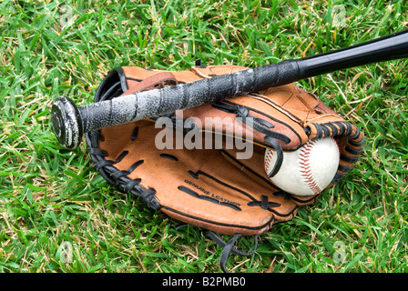 A baseball glove ball and bat lie in the grass before a game Stock Photo