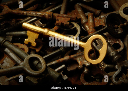 A gold brass skeleton key among a pile of old rusted antique keys Stock Photo