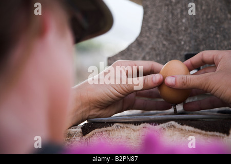 A tourist at the Solar Museum Intinian on the equator line tries to balance an egg on the nail near Quito in Ecuador. Stock Photo