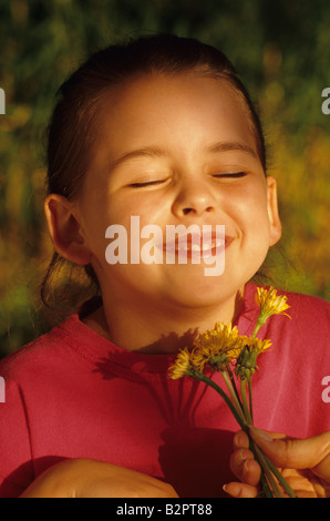 Young girl with dandelion put under her chin smiling summer game with mom 'likes butter' Bothell Washington State USA MR Stock Photo