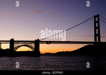 The south tower of Golden Gate Bridge and Fort Point silhouetted against sunset skies Stock Photo