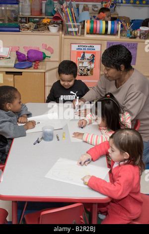 Preschool teacher helping her students learn to color Stock Photo