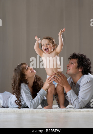 Parents helping baby to stand up Stock Photo