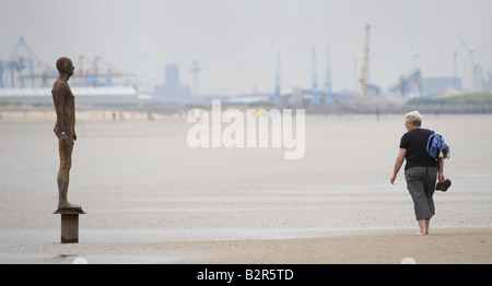 A WALKER LOOKS AT ONE OF THE IRON MEN STATUES ON CROSBY BEACH NEAR LIVERPOOL CREATED BY ARTIST ANTONY GORMLEY,UK,ENGLAND. Stock Photo