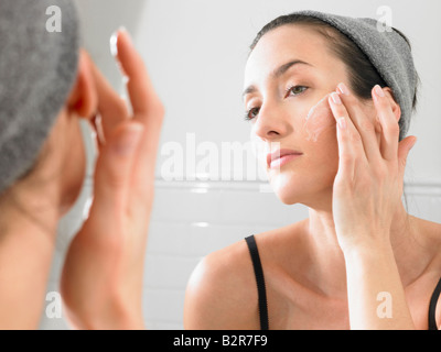 Woman putting on face cream Stock Photo