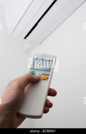 Adjusting the settings on a wall mounted air conditioning unit Stock Photo