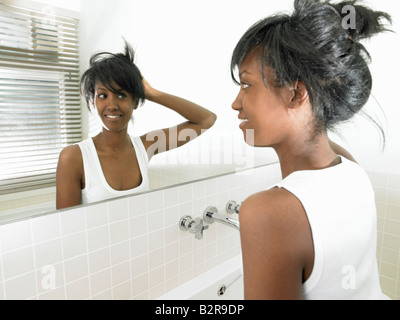Woman in bathroom, looking in the mirror Stock Photo