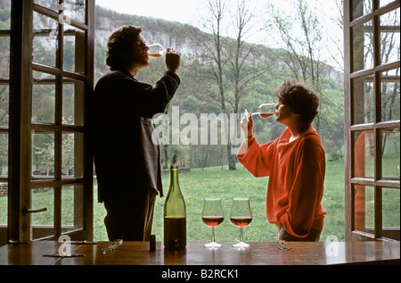 couple drinking wine in burgundy by their window Stock Photo