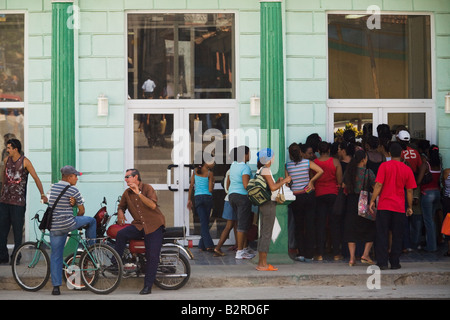 A group of people wait to enter a shop in Baracoa, Cuba Stock Photo