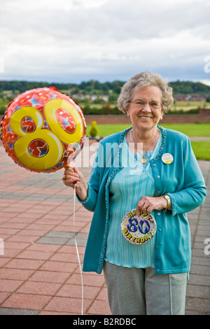 A SENIOR WOMAN HOLDING BALOON AT HER 80TH BIRTHDAY PARTY Stock Photo