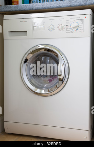 Britain UK White automatic washing machine and tumble dryer fully loaded up with laundry in water Stock Photo