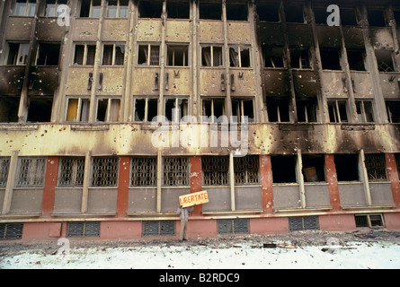 romania after the revolution person standing holding liberstate sign in front of burnt out bullet marked securitate building Stock Photo