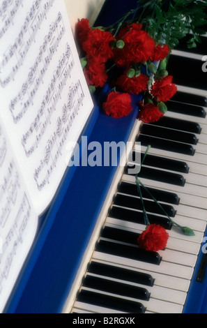 Old time blue piano with sheet music and roses on keyboard Lynnwood Washington State USA Stock Photo