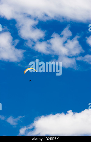 Man practicing paramenting paragliding extreme sport in a cloudy and blue sky. Stock Photo