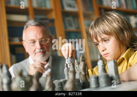 Young boy playing chess with grandfather Stock Photo