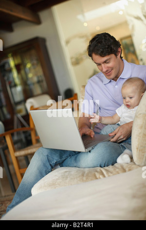 Father sitting at laptop with young son Stock Photo