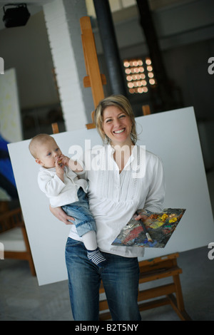 Mother holding baby in front of easel Stock Photo