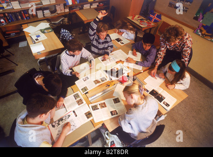 Overview of elementary school children at classroom desk reading and writing with teacher in Sweden Stock Photo