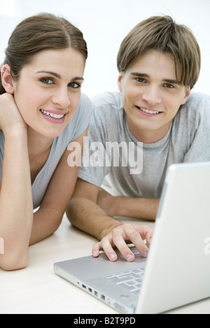 Woman and young male using laptop together, both smiling at camera Stock Photo
