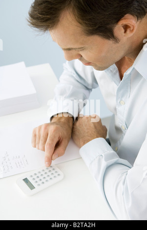 Man using calculator, sitting at table, high angle view Stock Photo