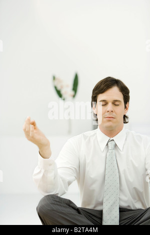 Businessman sitting in meditative position, eyes closed Stock Photo