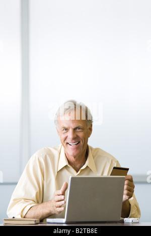 Man making on-line purchase with credit card, smiling at camera Stock Photo