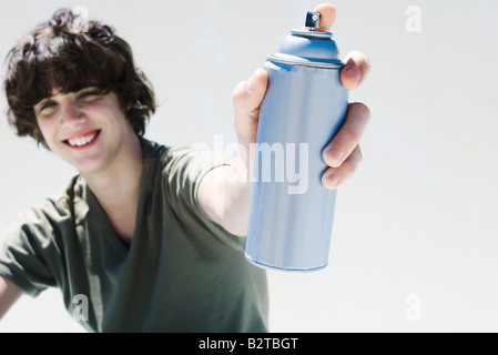 Teenage boy holding can of spray paint, smiling at camera