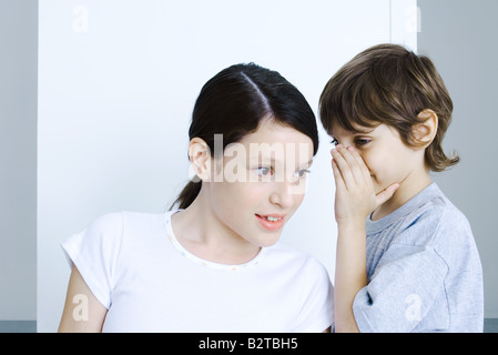 Brother whispering to his sister, hand covering mouth Stock Photo