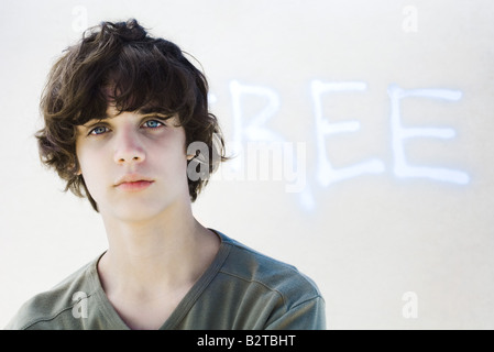 Teenage boy looking at camera, in front of graffiti