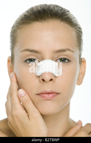 Woman with bandaged nose, looking at camera, portrait Stock Photo