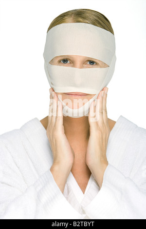 Woman with bandaged face, touching cheeks, looking at camera Stock Photo