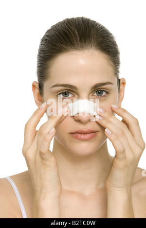 Young woman with bandaged nose, touching face, portrait Stock Photo