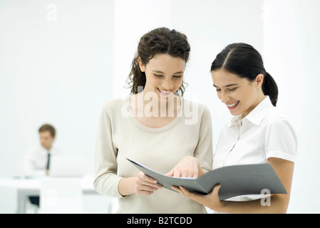 Female colleagues looking at document together, smiling Stock Photo