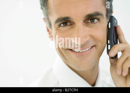 Man using cell phone, smiling at camera Stock Photo