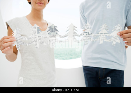 Young couple holding ends of cut out paper trees, cropped view Stock Photo