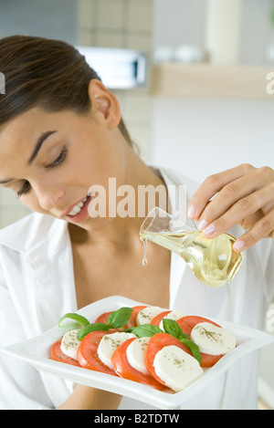 Woman pouring olive oil on antipasto Stock Photo