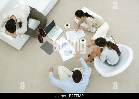 Colleagues discussing documents, two sitting on the floor, one resting head on arms, overhead view Stock Photo